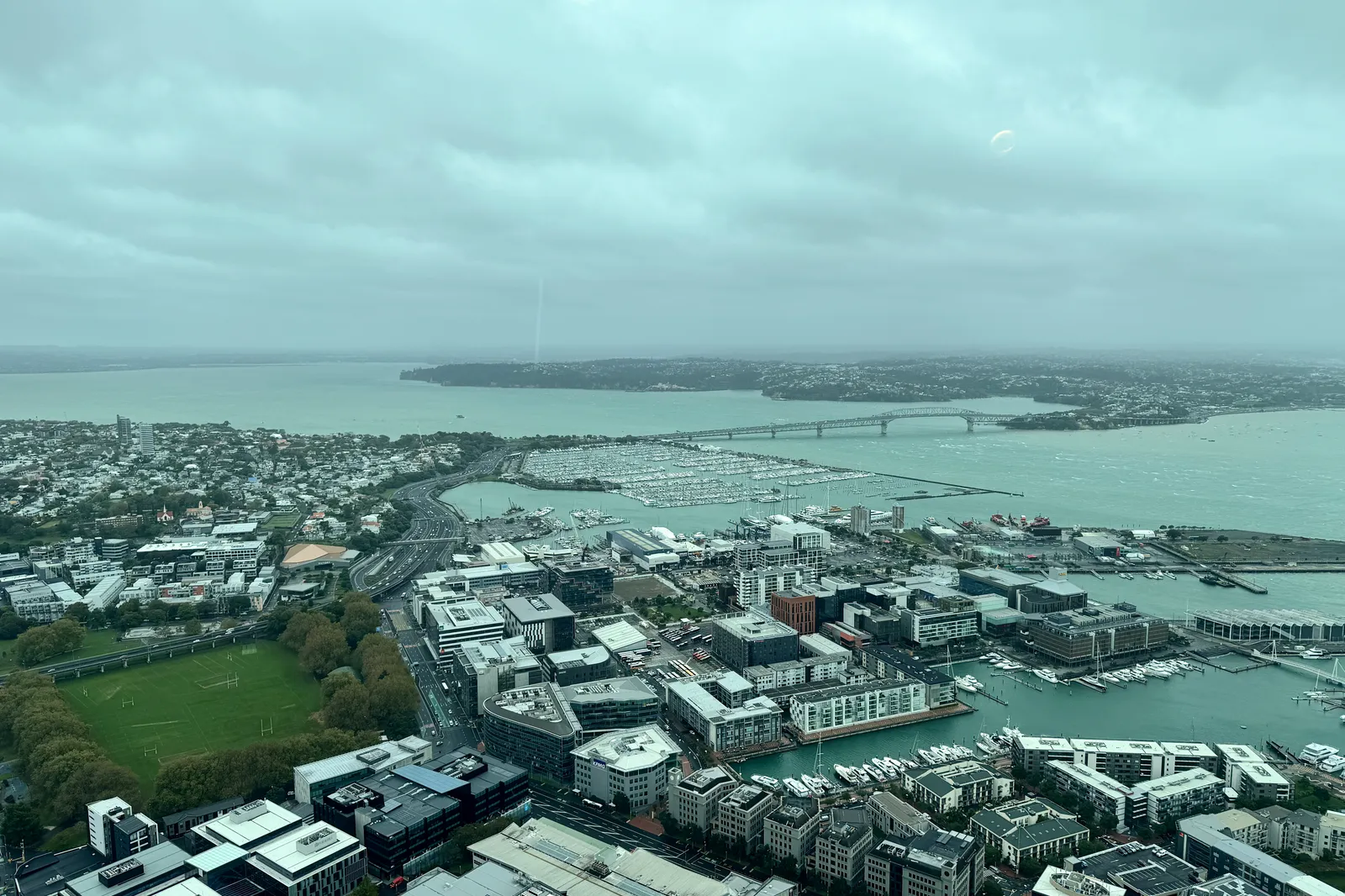 Auckland's waterfront, marinas and Harbour Bridge seen from the Sky Tower under gray skies
