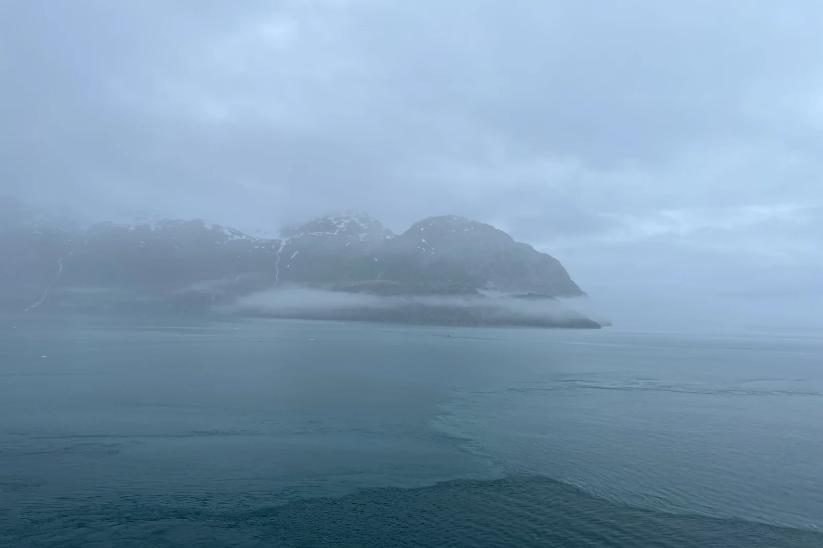 Low cloud over the snow-streaked mountains of Glacier Bay National Park, seen from an Alaska cruise ship
