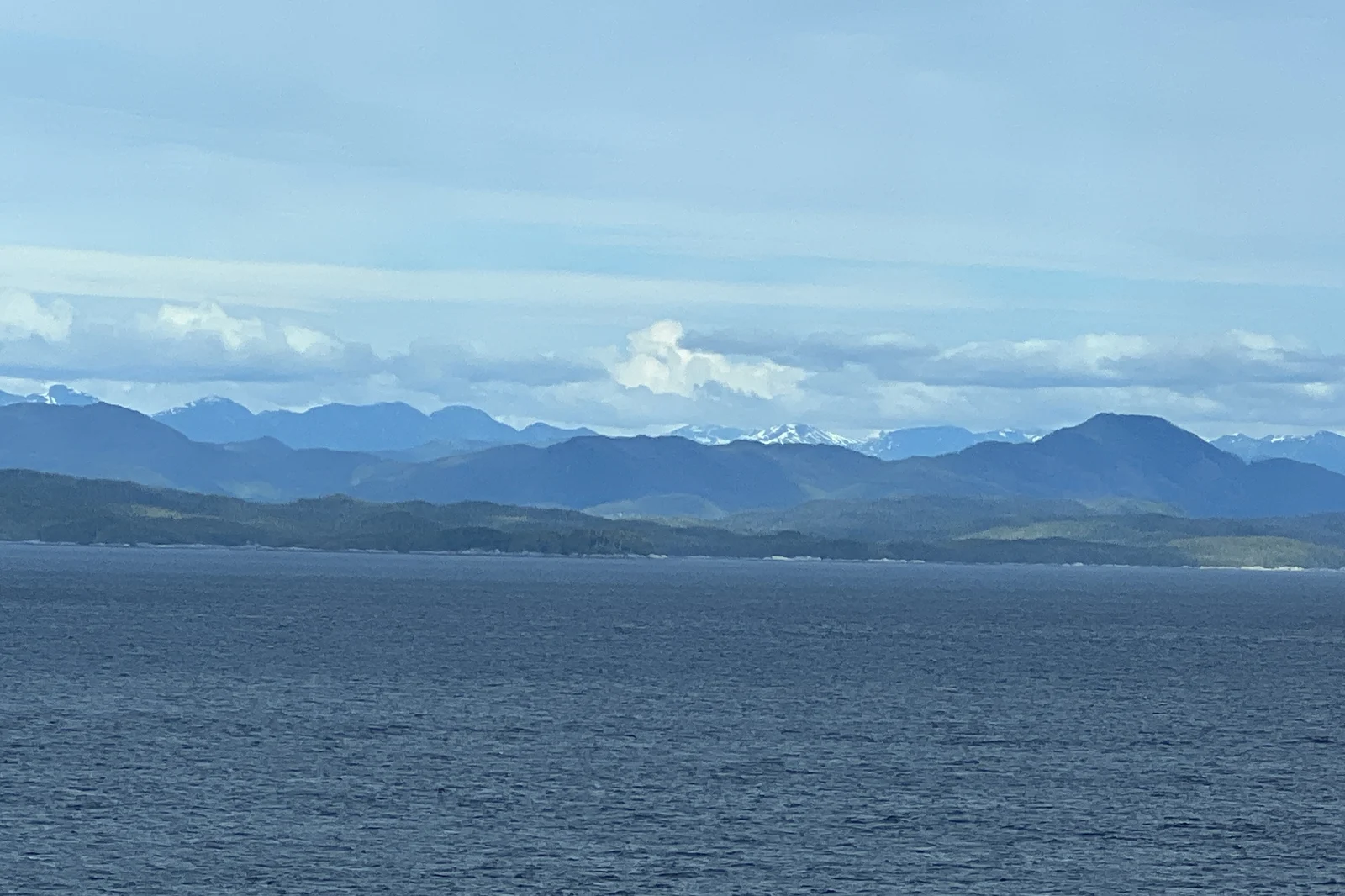 Snow-capped mountains along the Inside Passage seen from the deck of an Alaska cruise ship