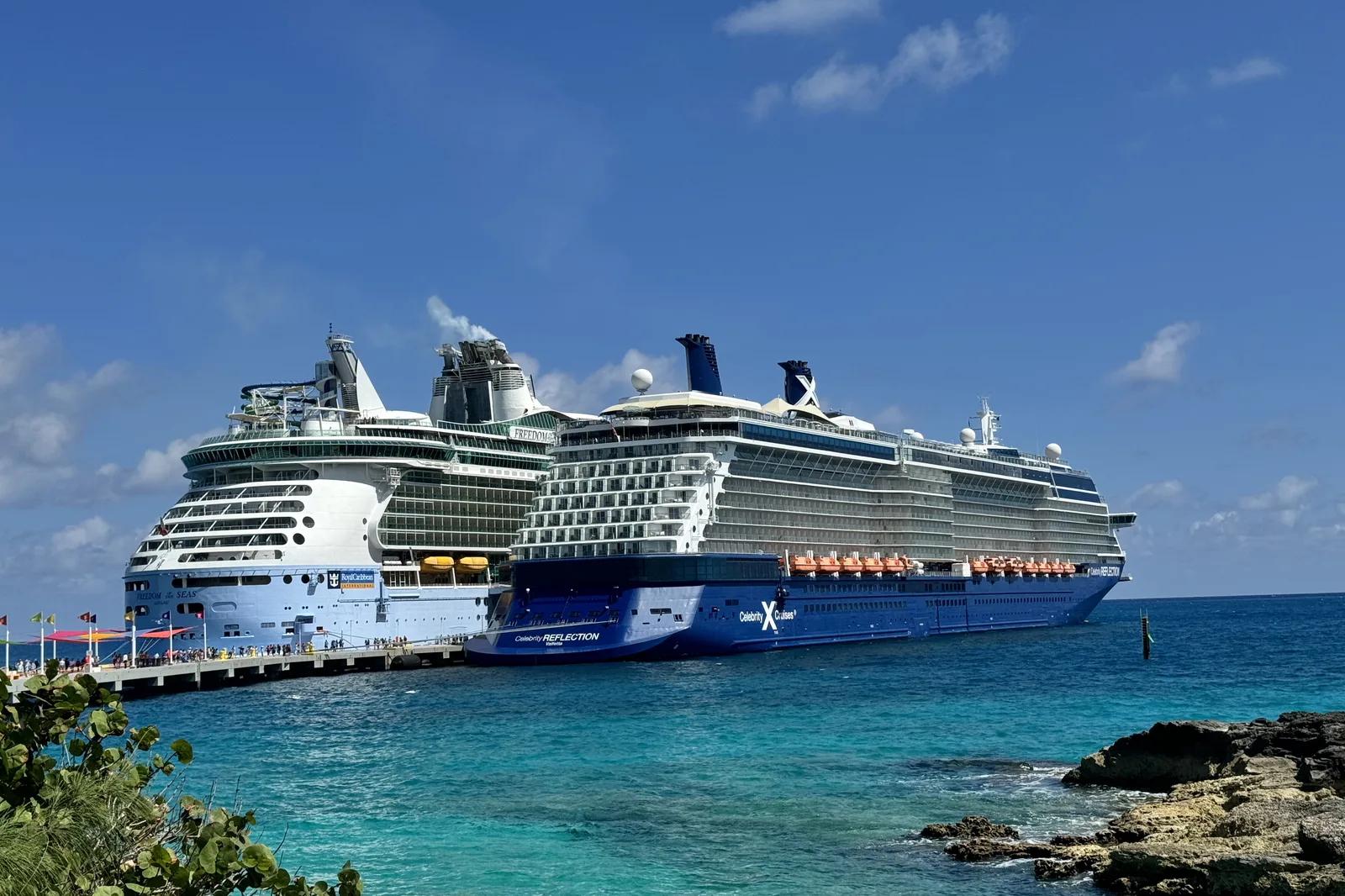 A large cruise ship alongside the pier at a Bahamian private island, with turquoise water in the foreground
