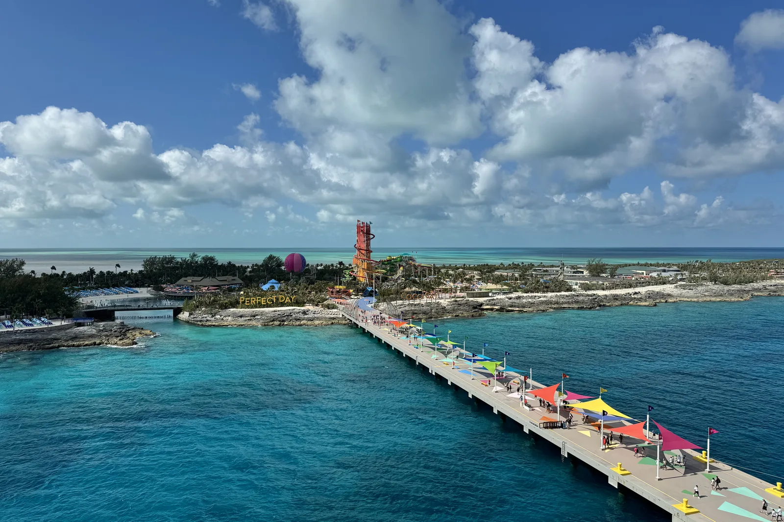 The pier at a Caribbean private island seen from above, lined with umbrellas and surrounded by shallow turquoise water