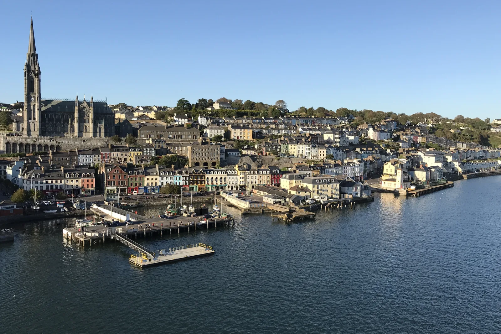 The town of Cobh in Ireland seen from a cruise ship, with St Colman's Cathedral above the painted terraces and the pier below