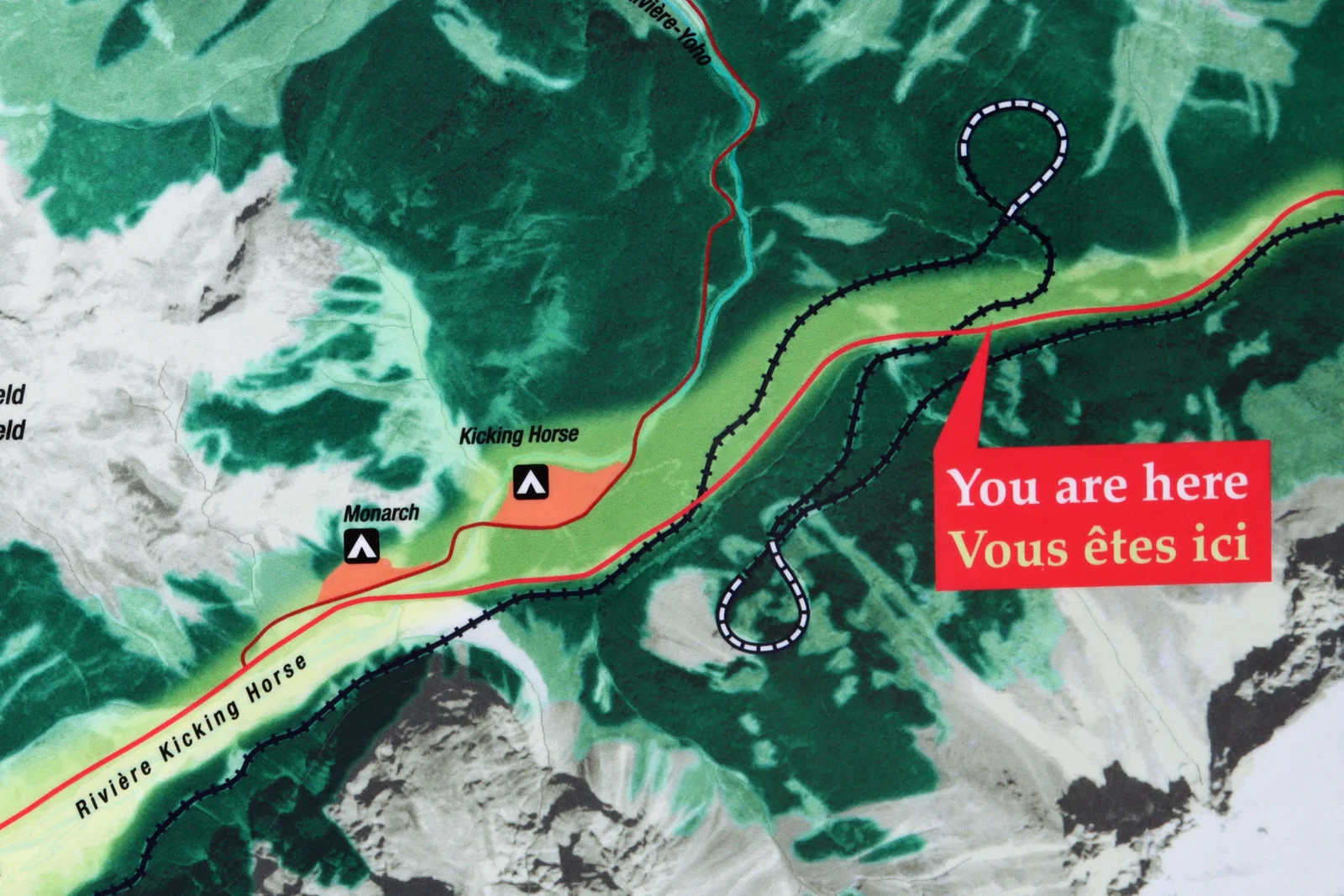 Trail map at the Spiral Tunnels viewpoint in Yoho National Park, showing the railway tracing two figure-eight loops inside the mountains beside the Kicking Horse River, with a You are here marker