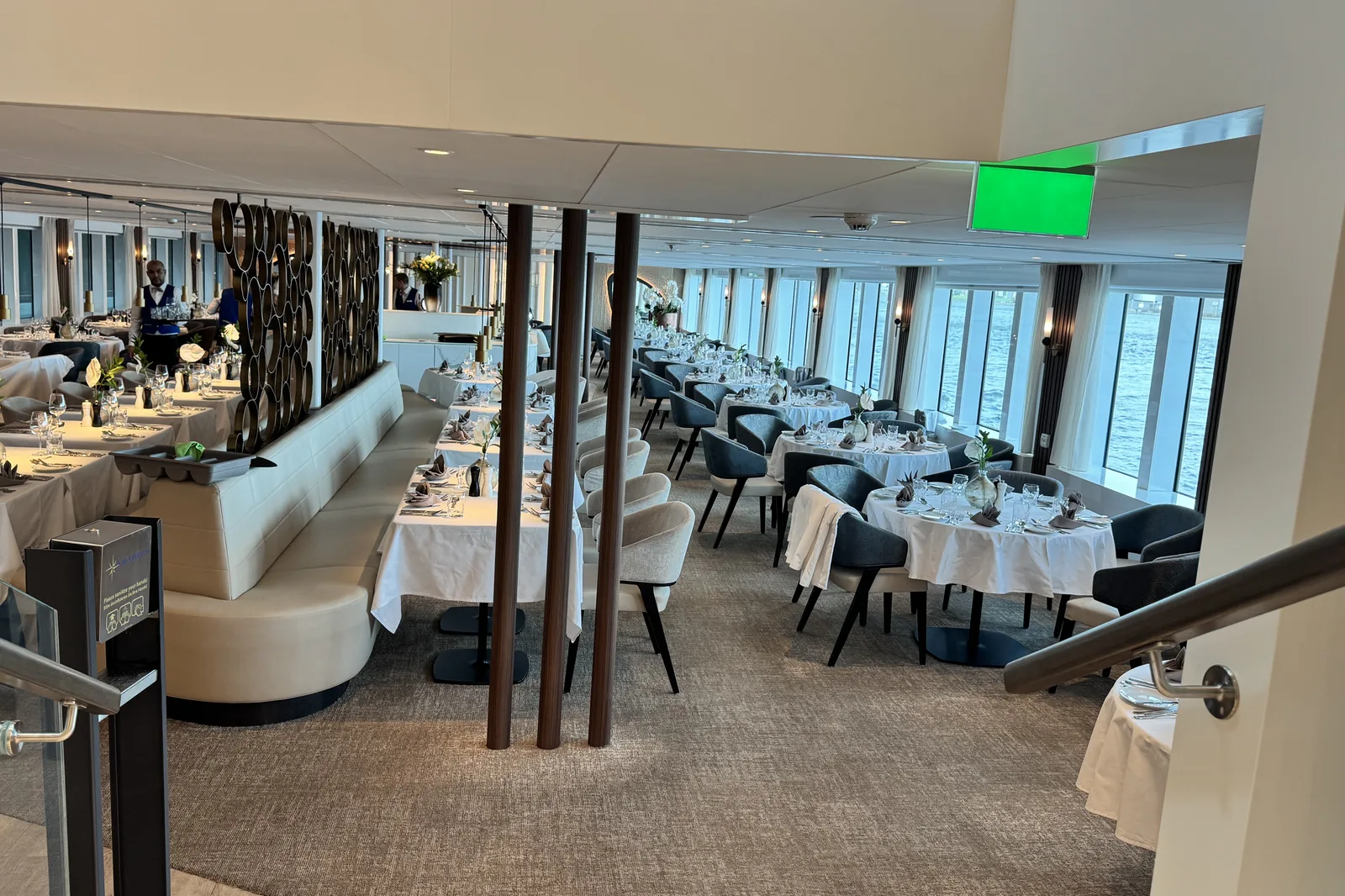 The dining room of a river ship, tables set beside floor to ceiling windows