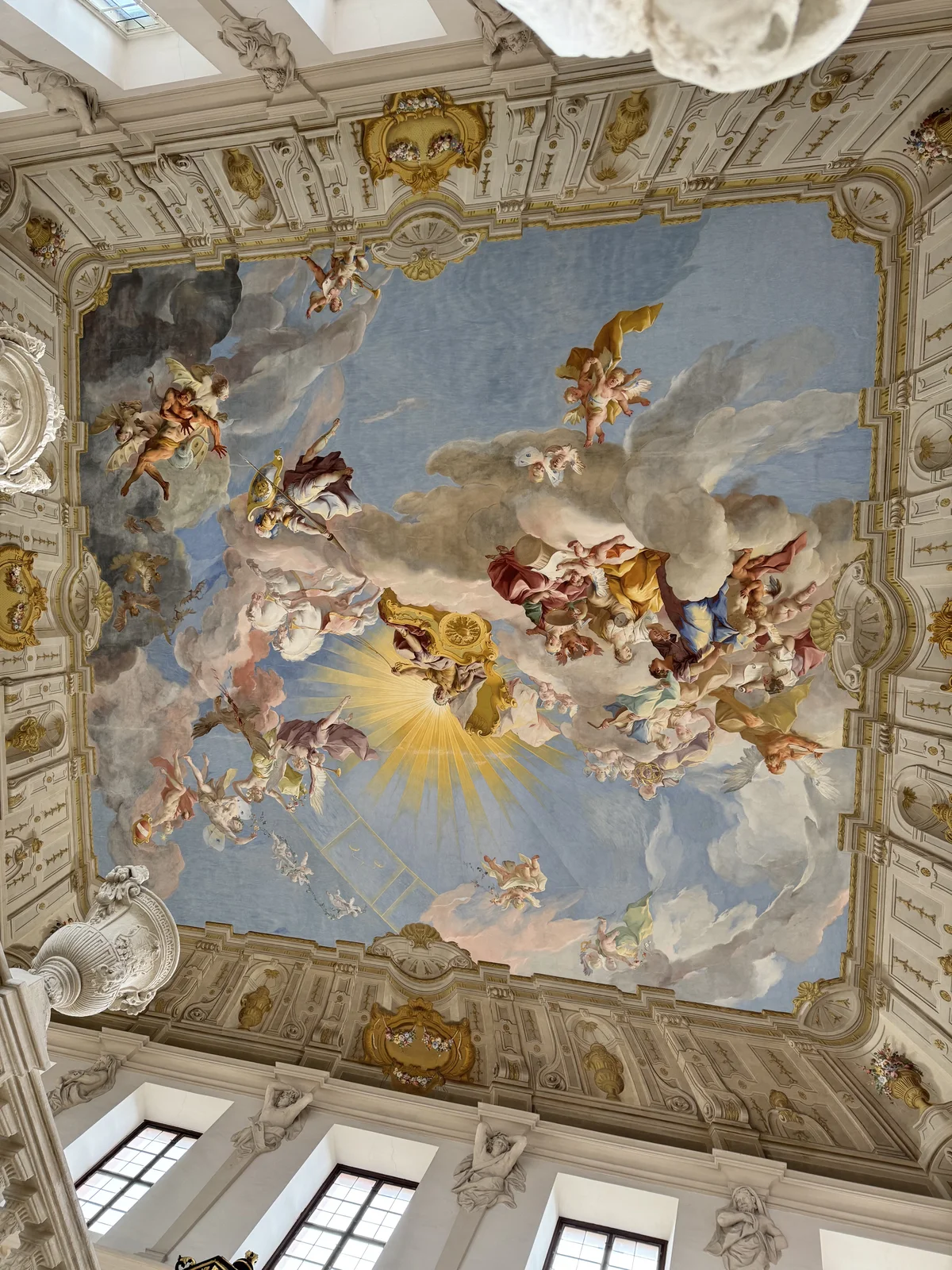 The painted ceiling fresco inside Göttweig Abbey above the Danube, angels and clouds framed in gold and stucco.