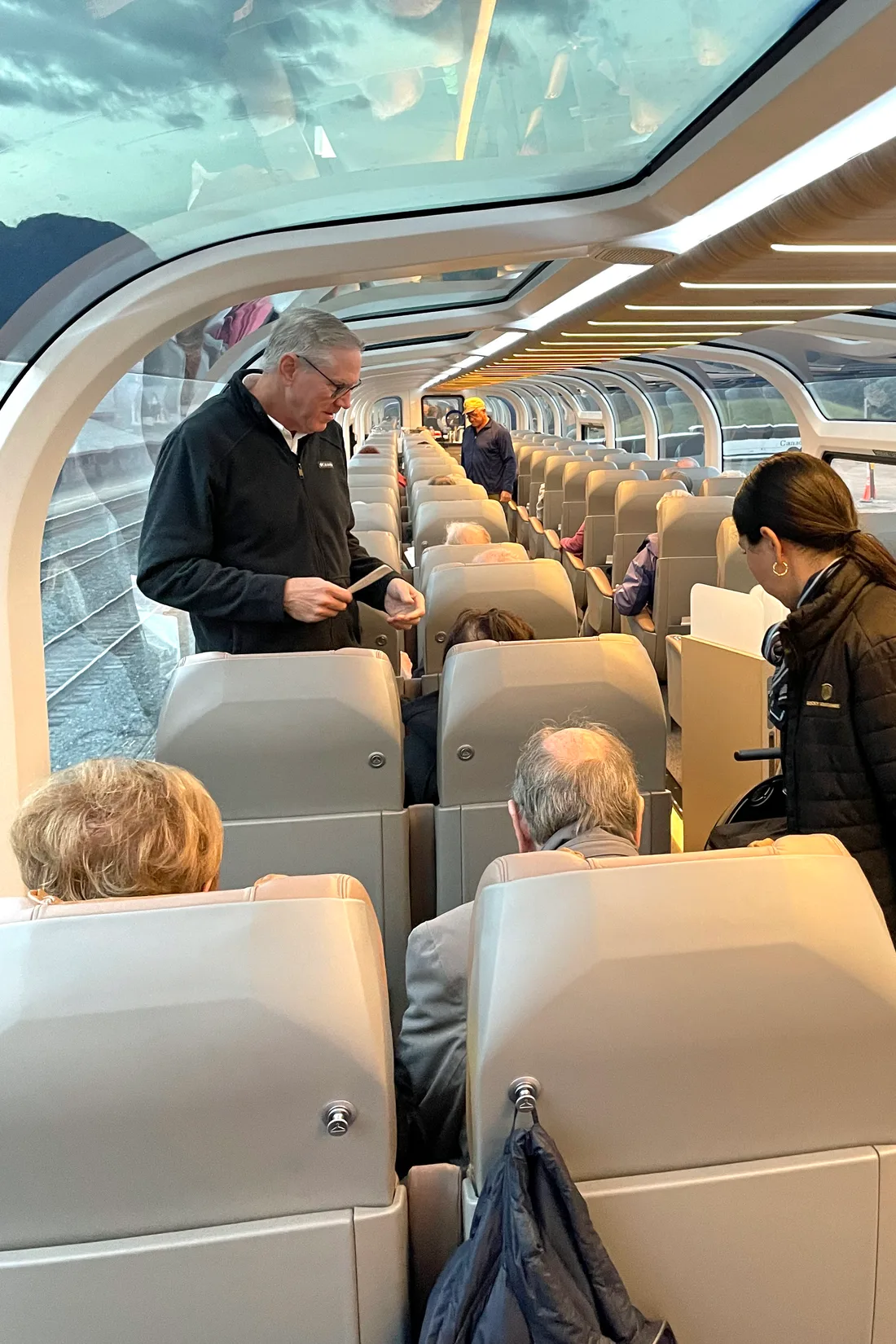A GoldLeaf host serving guests beneath the glass dome aboard Rocky Mountaineer.