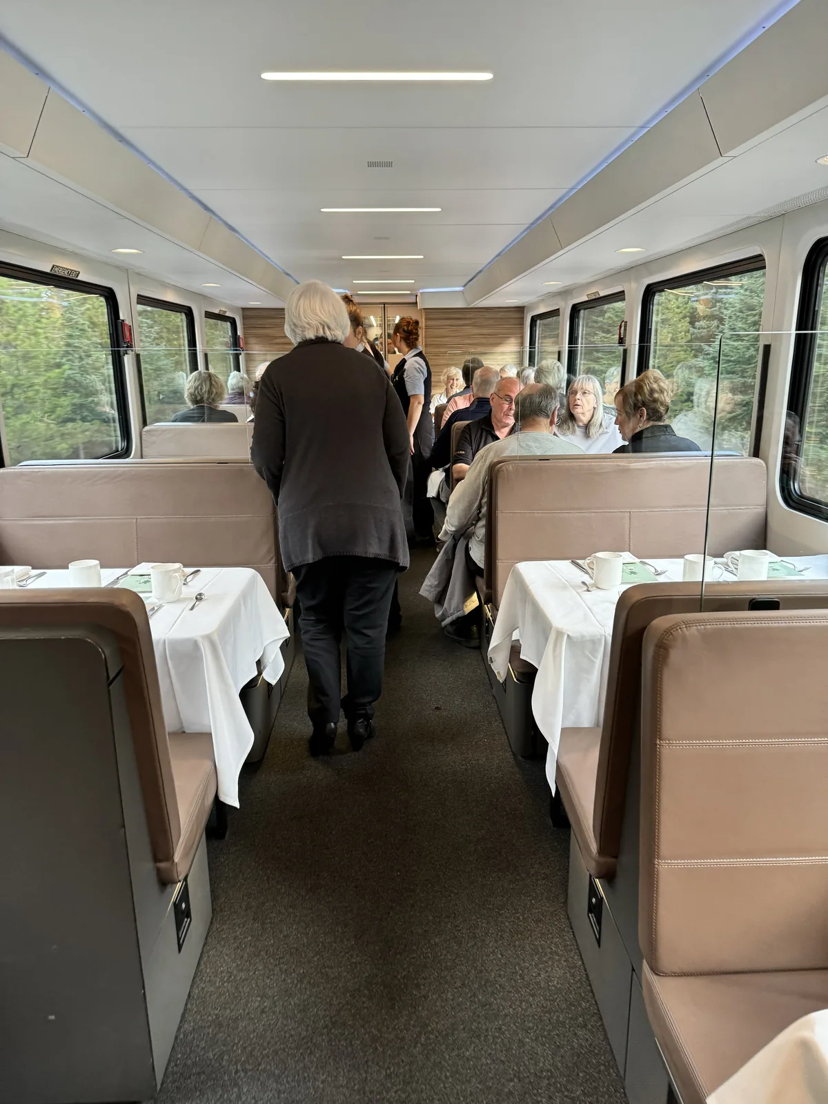 Inside a Rocky Mountaineer GoldLeaf dining car with white-linen tables.