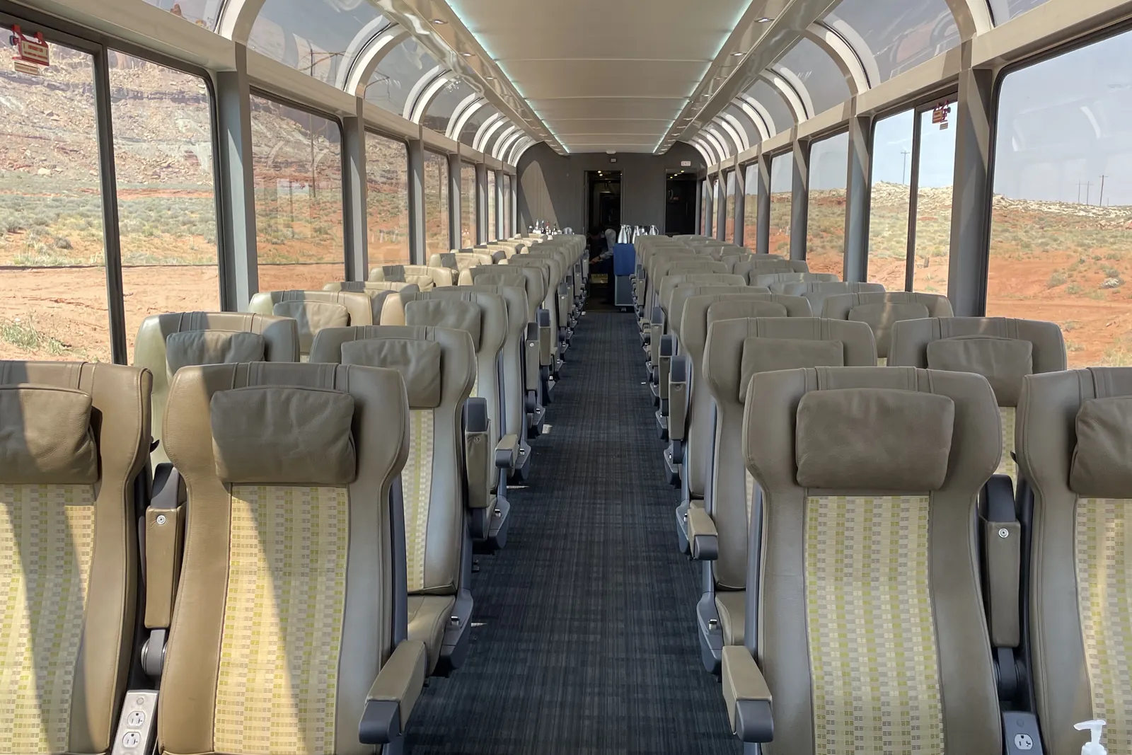 Inside Rocky Mountaineer's single-level glass-dome coach on the Canyon Spirit route, seats beneath the domed windows with red rock country outside