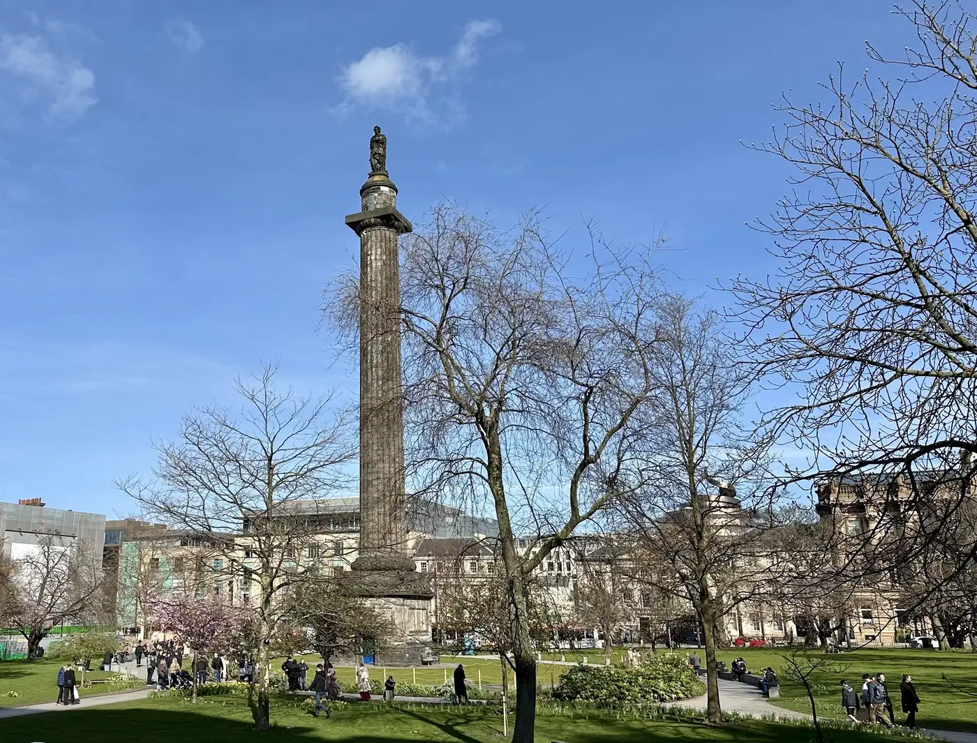 A leafy square in Edinburgh's New Town, the Melville Monument column rising over people walking on a bright spring day