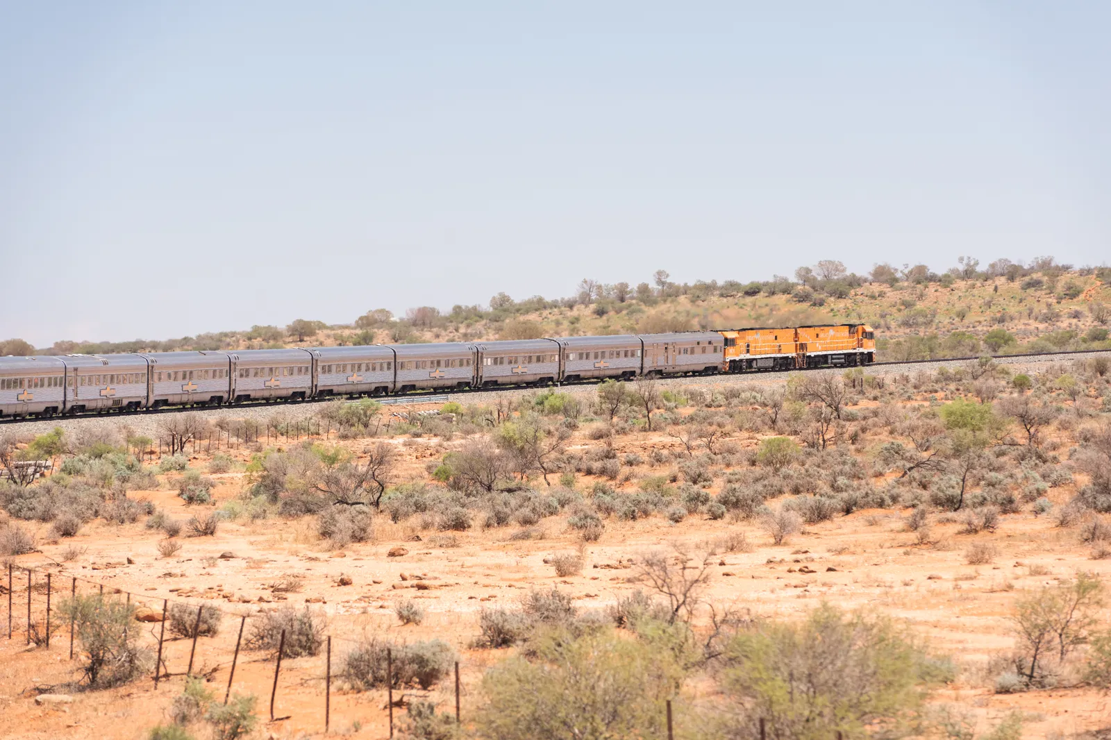 The Great Southern train crossing red outback scrubland under a pale sky