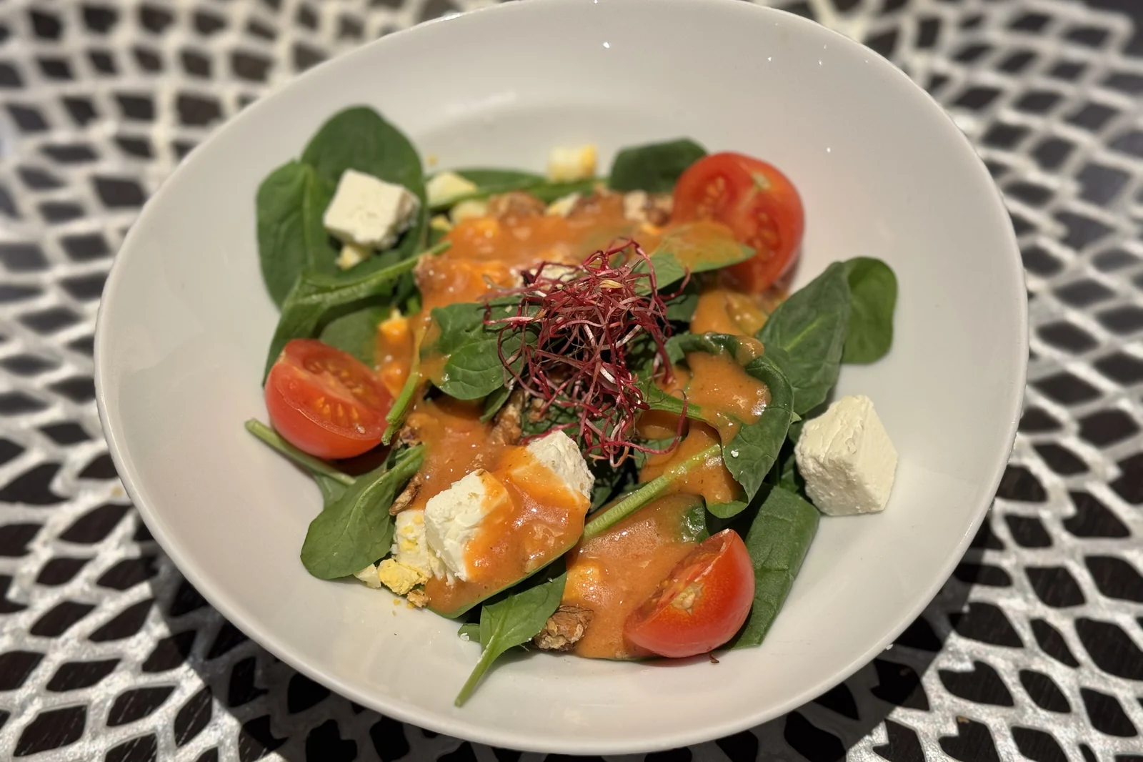 A fresh spinach salad with tomatoes, feta, and walnuts plated aboard a river cruise ship
