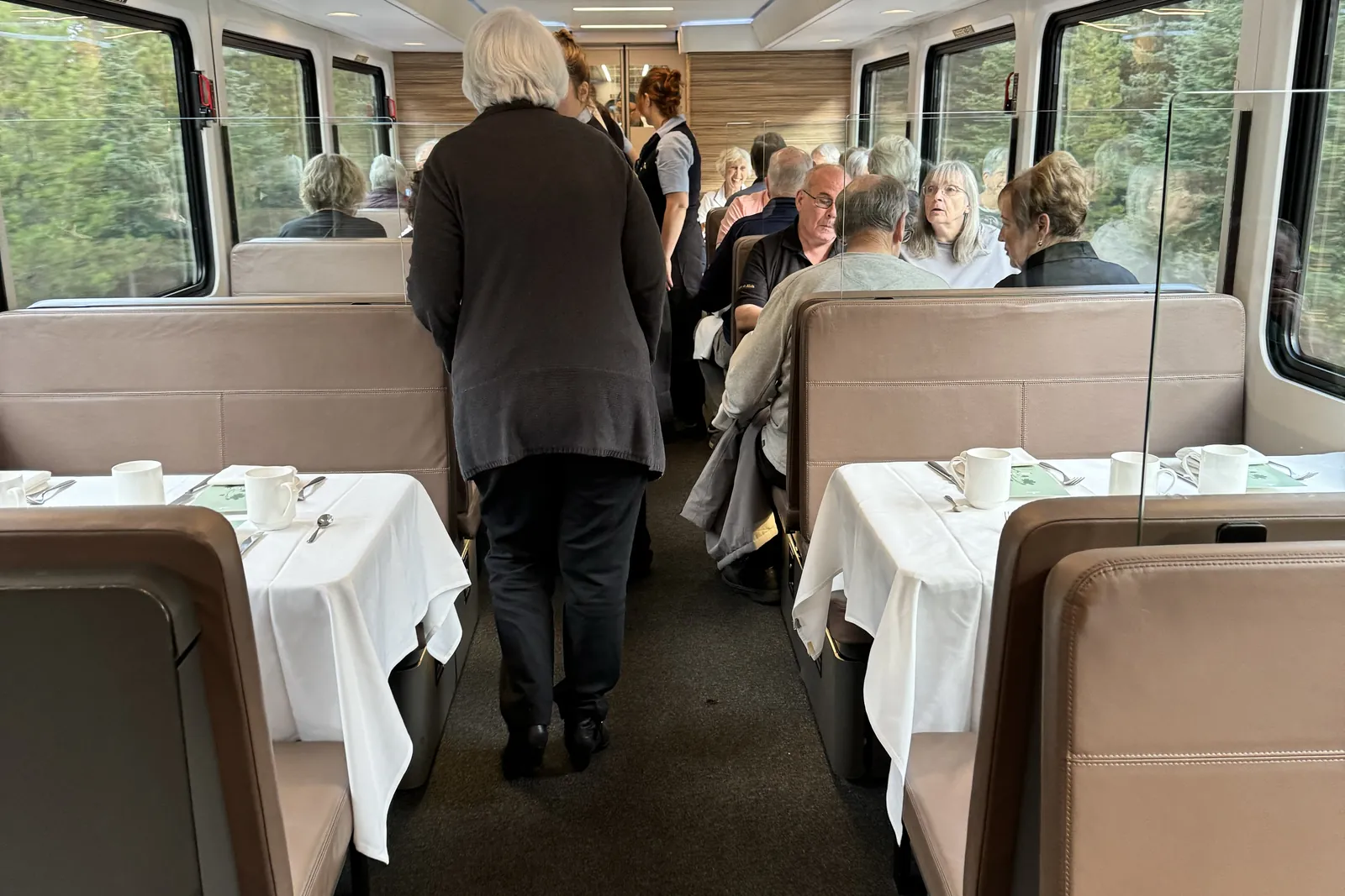 Inside Rocky Mountaineer's GoldLeaf dome coach, tables set with white linens beneath the glass-domed windows
