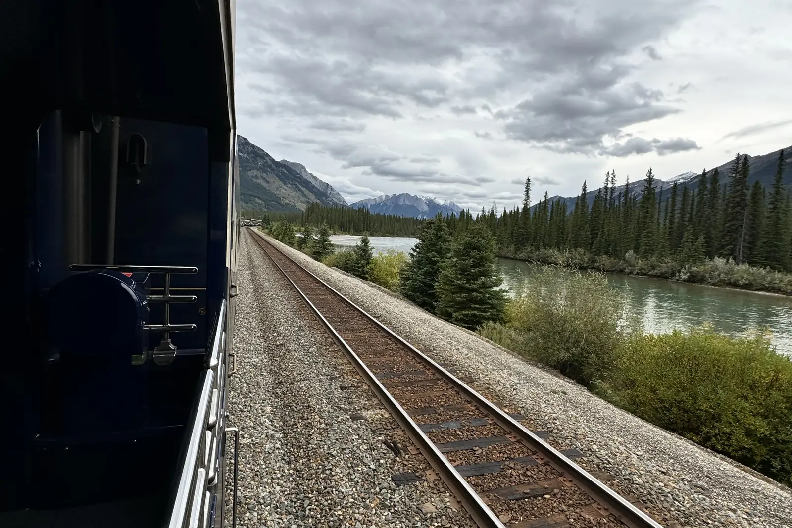 The railway tracks curving along a river through the Canadian Rockies, seen from aboard the Rocky Mountaineer