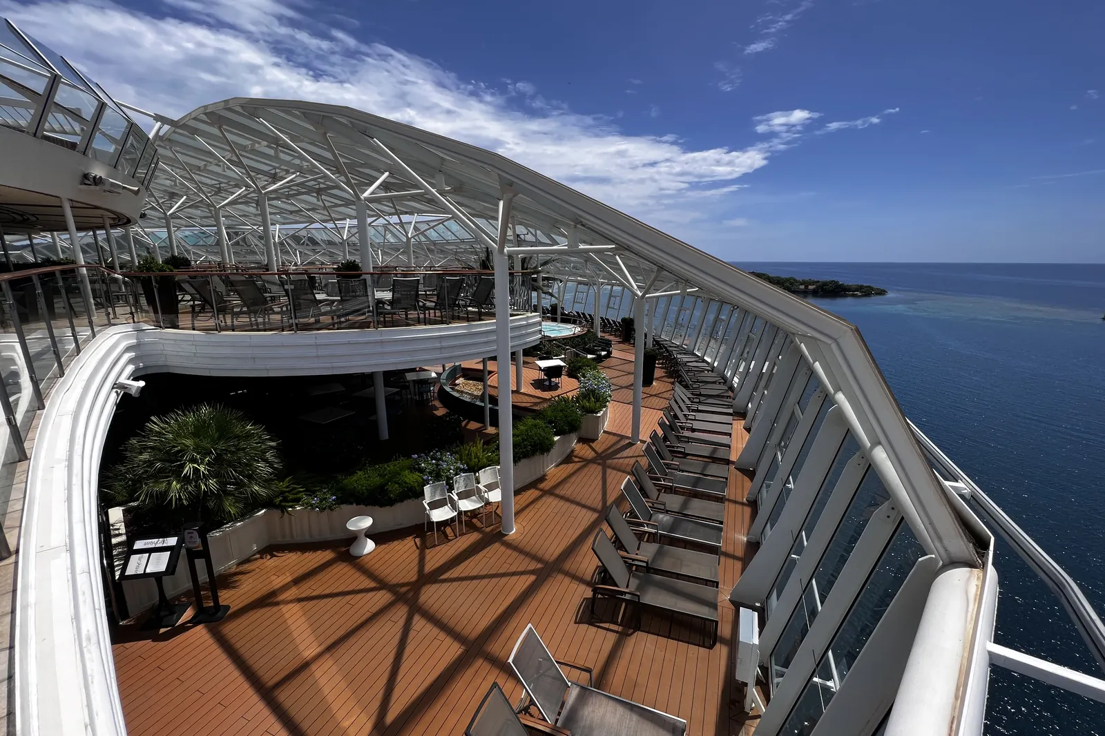 The glass-domed Solarium deck aboard Royal Caribbean's Allure of the Seas, loungers beneath the arched glass with the sea beyond