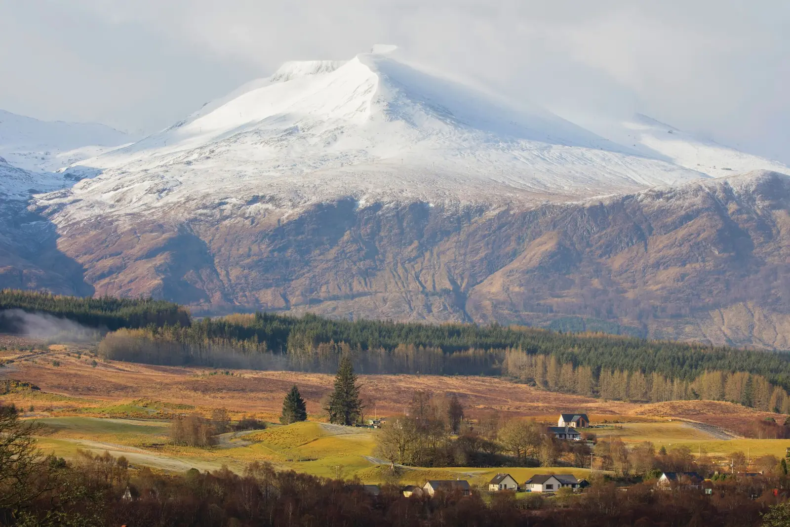 A snow-capped mountain above a Highland village, the kind of scenery the Royal Scotsman train travels through