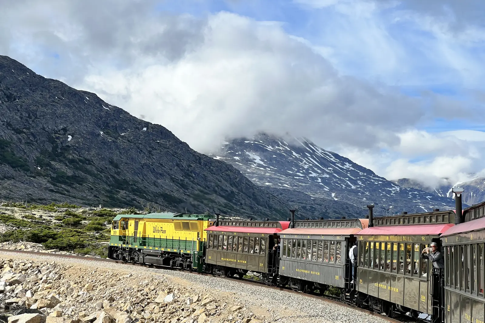 A White Pass and Yukon Route train winding along a cliffside above the valley on the climb out of Skagway, Alaska